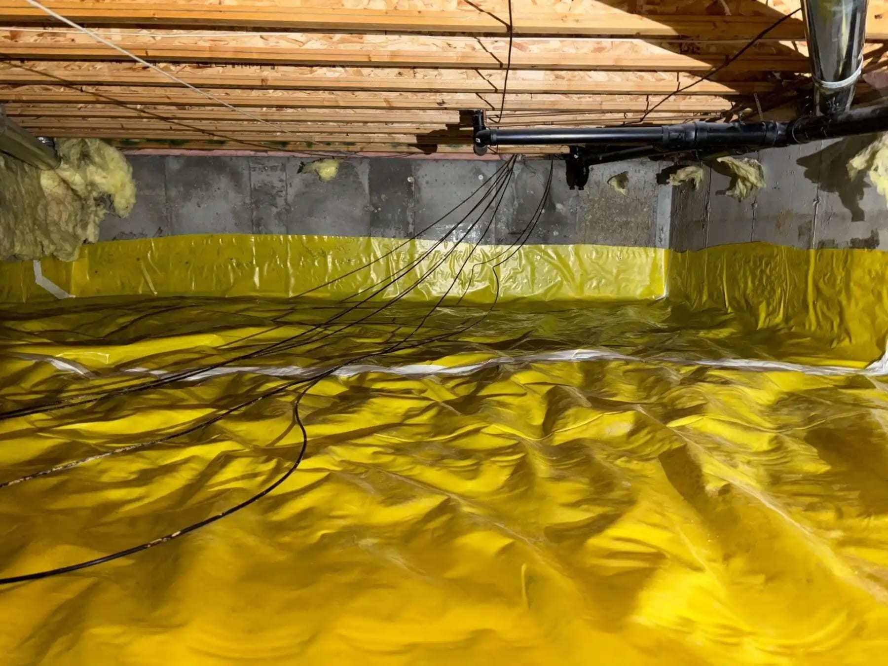 Crawlspace floor and walls sealed with a yellow vapor barrier