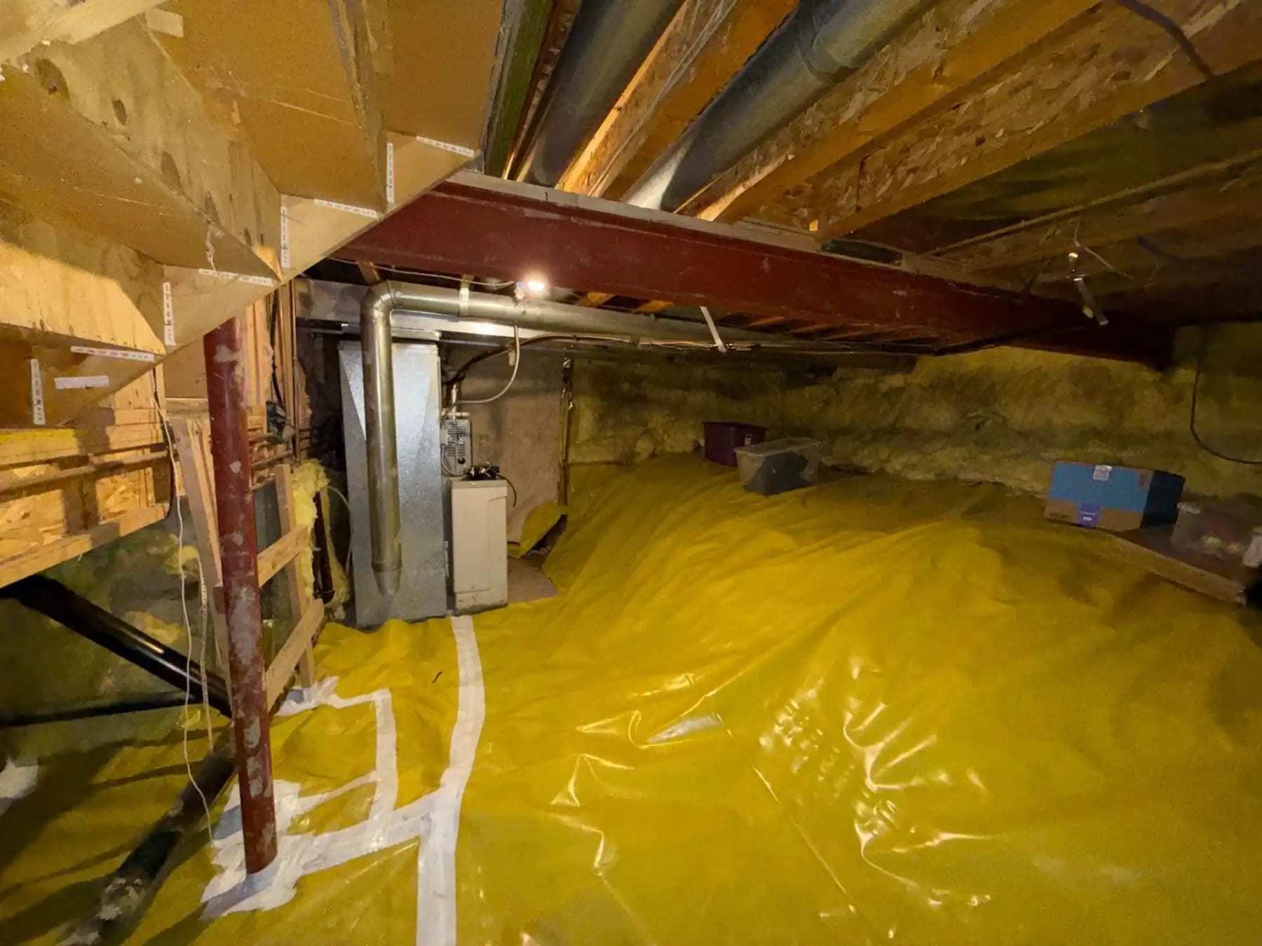 Crawlspace with a vapor barrier laid around a furnace and ductwork