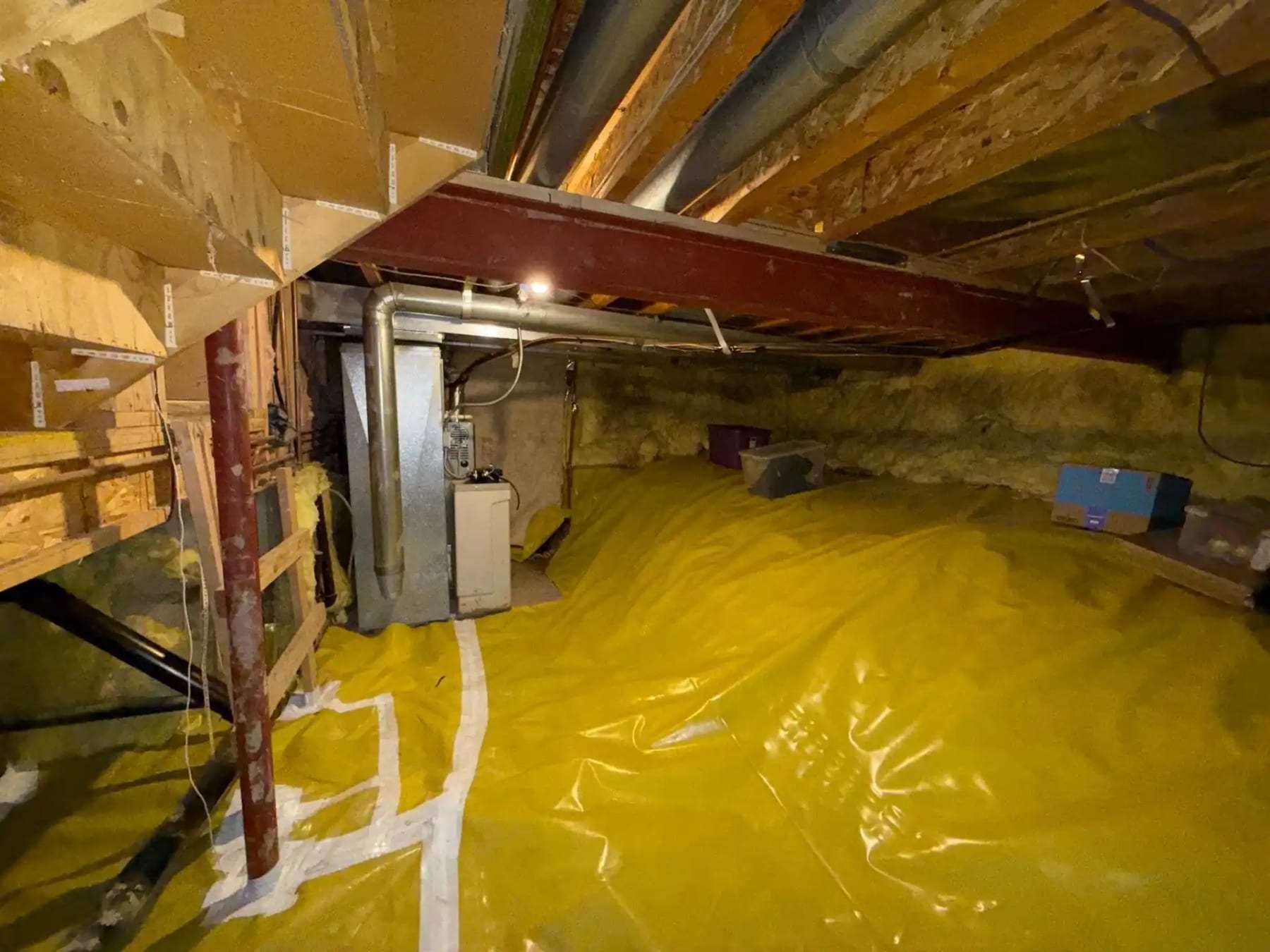 Crawlspace with a vapor barrier laid around a furnace and ductwork
